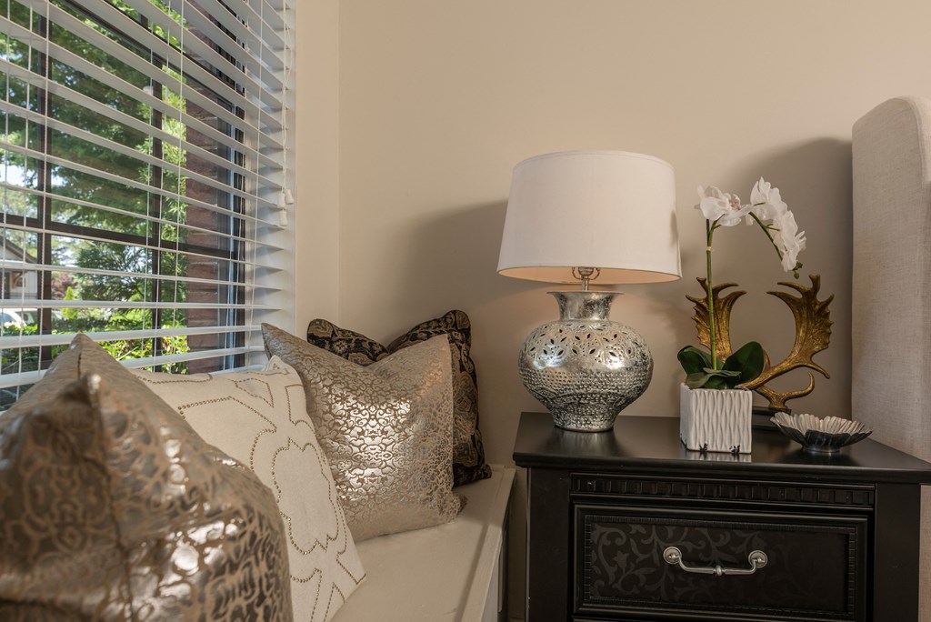 a living room with a lamp and pillows and a window