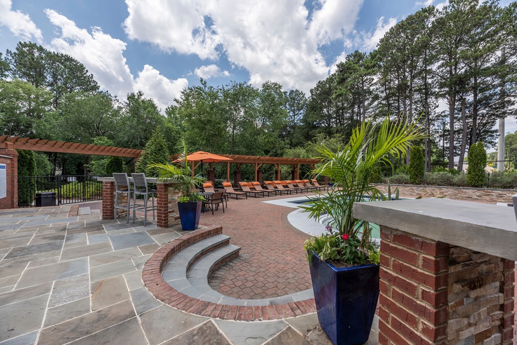 a patio with brick pillars and a seating area with potted plants