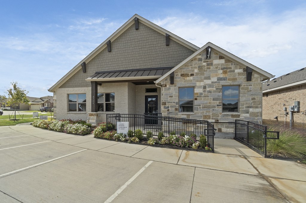 the front of a brick house with a driveway and a black fence