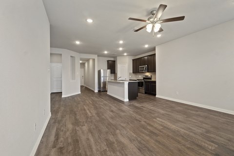 an empty living room and kitchen with a ceiling fan