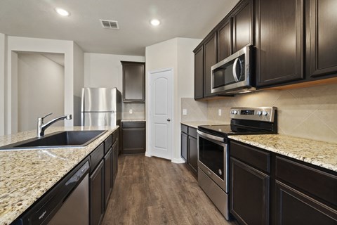 a kitchen with granite counter tops and black cabinets and stainless steel appliances