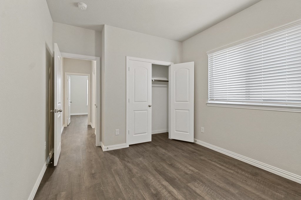 the spacious living room of an apartment with white walls and wood flooring