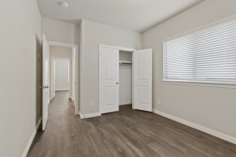 the spacious living room of an apartment with white walls and wood flooring