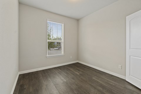 Two-Bedroom Rental Homes in Lewisville, TX - The Villas at Rockbrook - Bedroom with Wood-Style Hard Surface Flooring and Window.