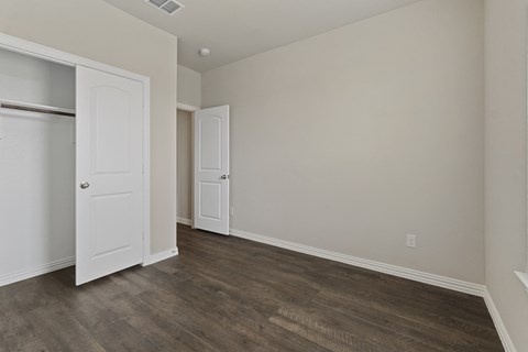 an empty bedroom with a closet and a door open
