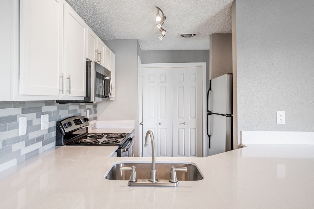 a white kitchen with a sink and a refrigerator