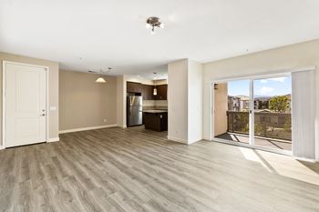 a living room with hardwood floors and a sliding glass door to a balcony
