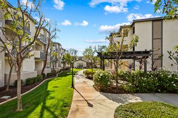 a view of an apartment complex with green grass and trees