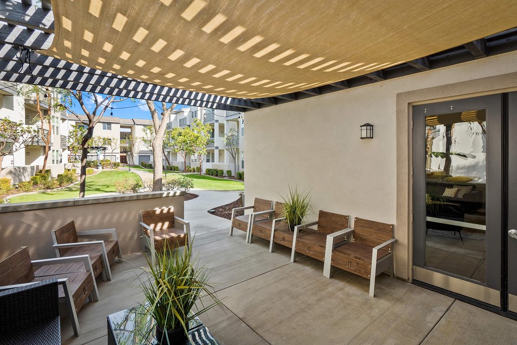 a patio with wooden benches and chairs and a black and white awning