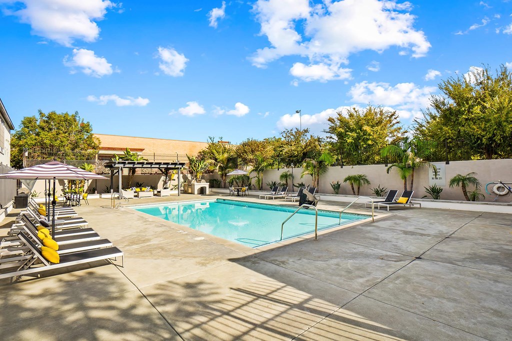 a swimming pool with lounge chairs and umbrellas in front of a building