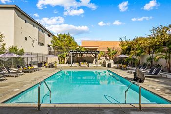 a swimming pool with lounge chairs and umbrellas in front of a hotel