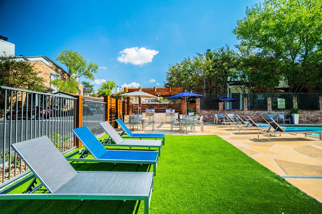 the backyard has a pool and lounge chairs and a lawn