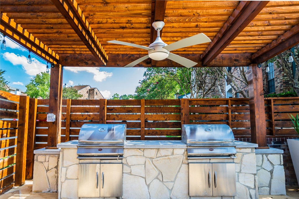 a covered outdoor entertaining area with a barbecue grill and a ceiling fan