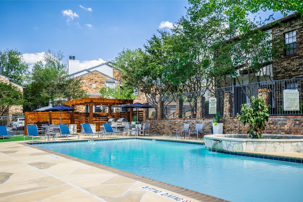 a swimming pool with chairs and umbrellas in front of a building