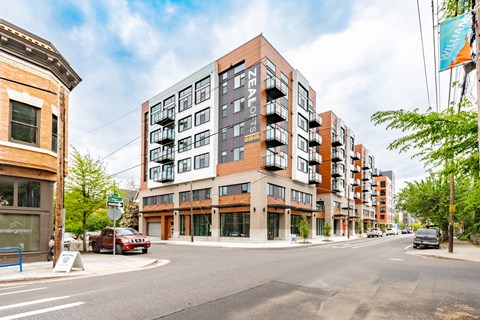 A street view of a residential area with apartment buildings and cars.