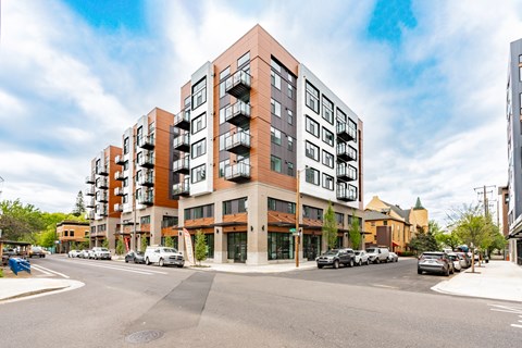 A modern apartment building with a parking lot in front.