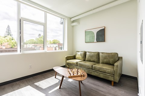A living room with a green couch and a chess set on the table.
