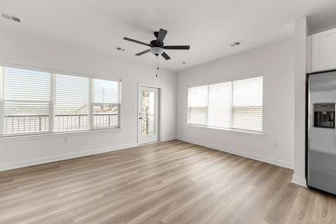 A spacious room with a ceiling fan and wooden flooring.