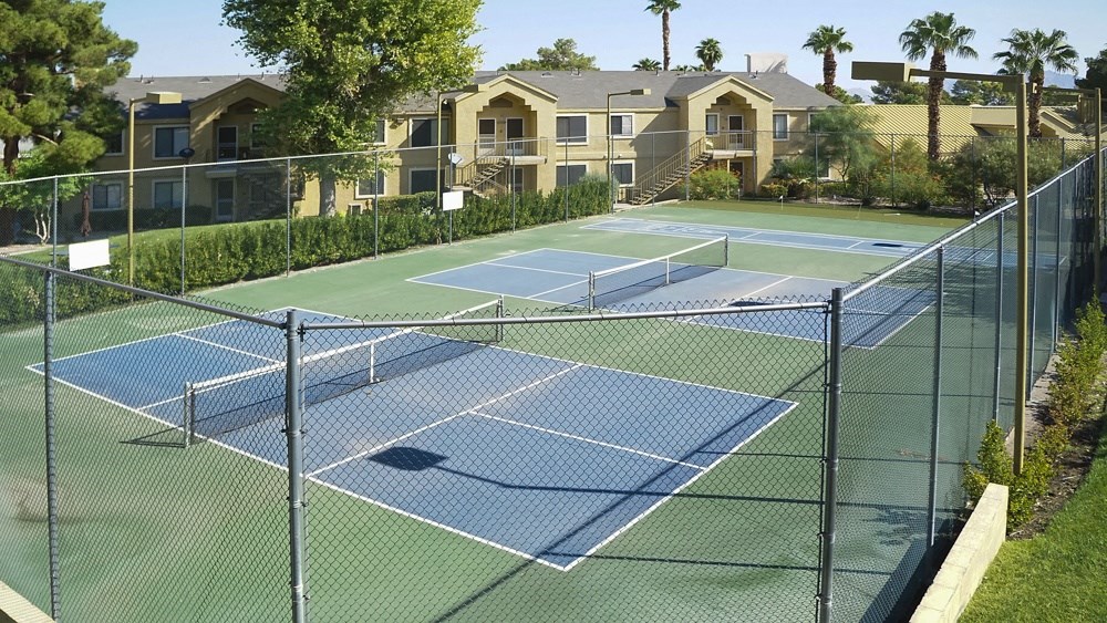 two tennis courts at the resort with apartments in the background