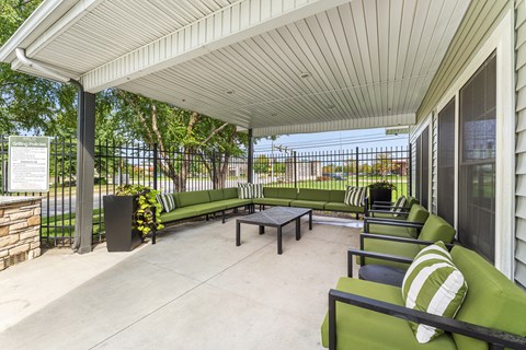 A patio with a white roof and green couches.