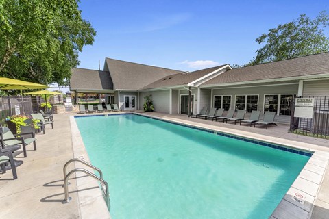 A pool with a metal railing and a house in the background.