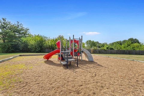 A playground with a red slide and a wooden structure.