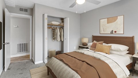 A bedroom with a large bed and a closet with clothes hanging.