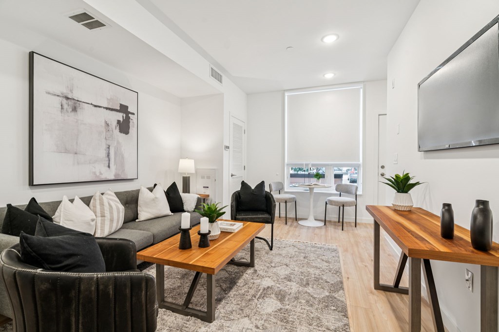 A modern living room with a grey couch, a wooden coffee table, and a large abstract painting on the wall.