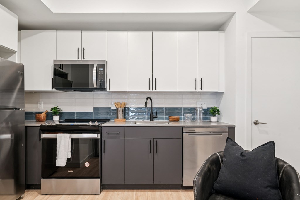 A modern kitchen with a black chair and a black pillow.
