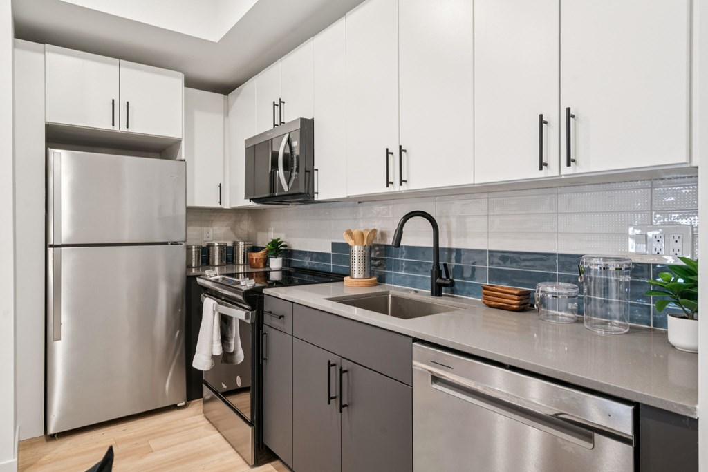 A modern kitchen with a stainless steel refrigerator and black cabinets.