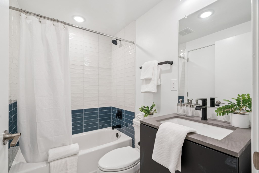 A bathroom with a white toilet, a white shower curtain, and a white sink.