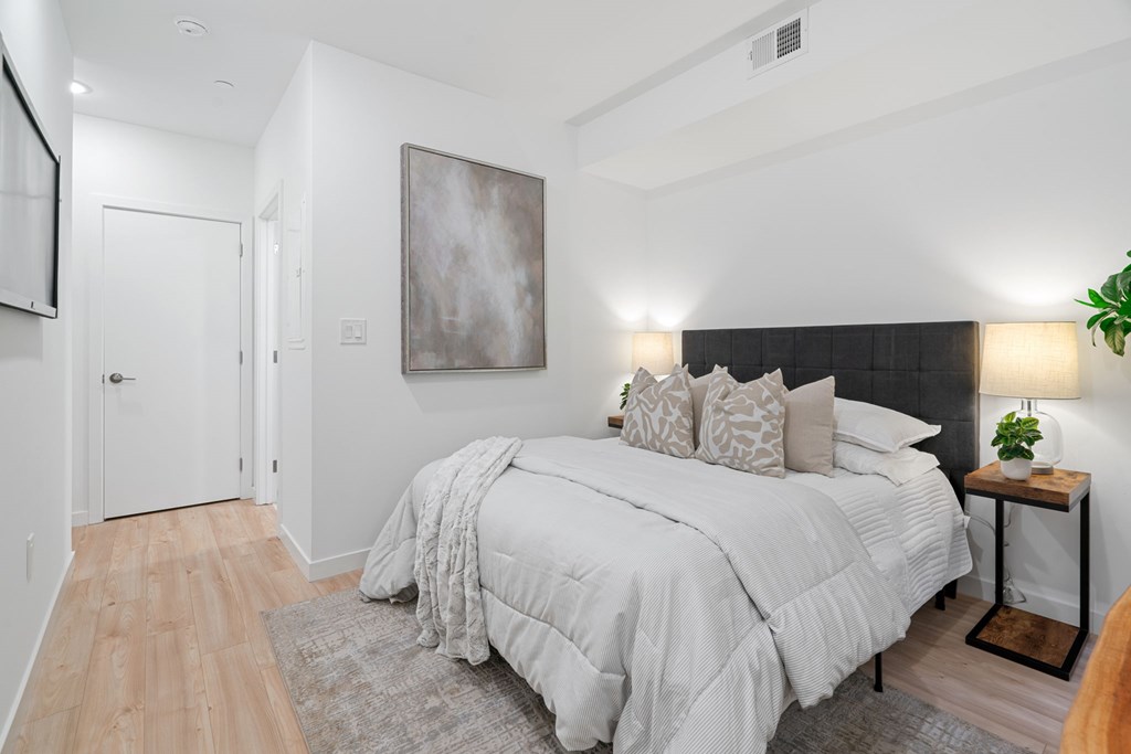 A bedroom with a large bed and a painting on the wall.