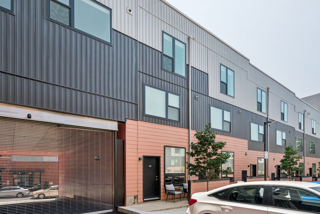 A modern building with a black and pink facade and a car parked in front.