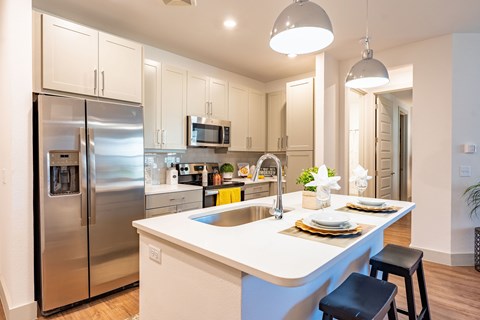 A modern kitchen with a stainless steel refrigerator and a white island.