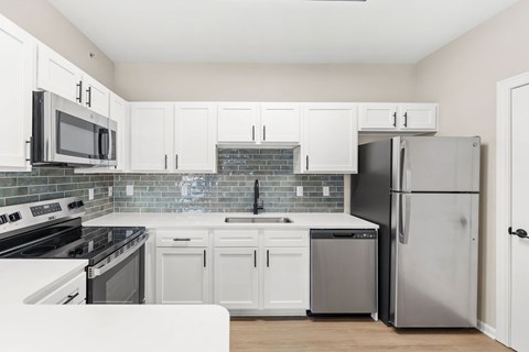 A kitchen with white cabinets and appliances.