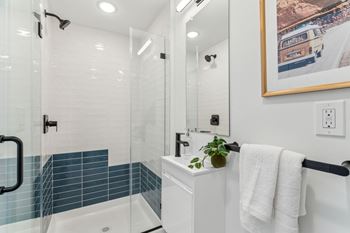 A white bathroom with a blue tiled shower.