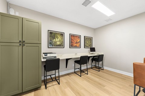 A room with a desk, chairs, and pictures on the wall.