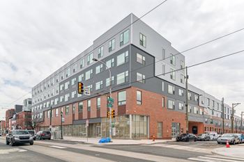 A modern building with a glass facade is situated on a street corner.