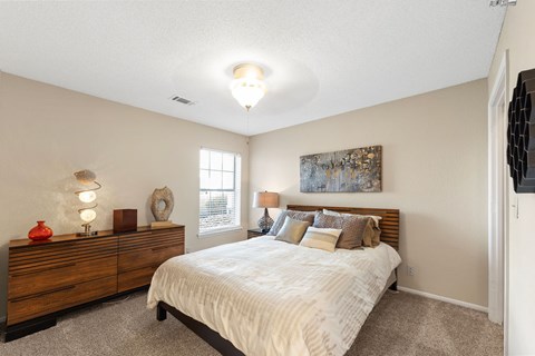 A bedroom with a bed, dresser, and window.