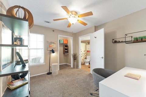 A room with a ceiling fan and a white table with a book on it.