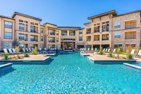 A large swimming pool in front of a multi-story residential building.