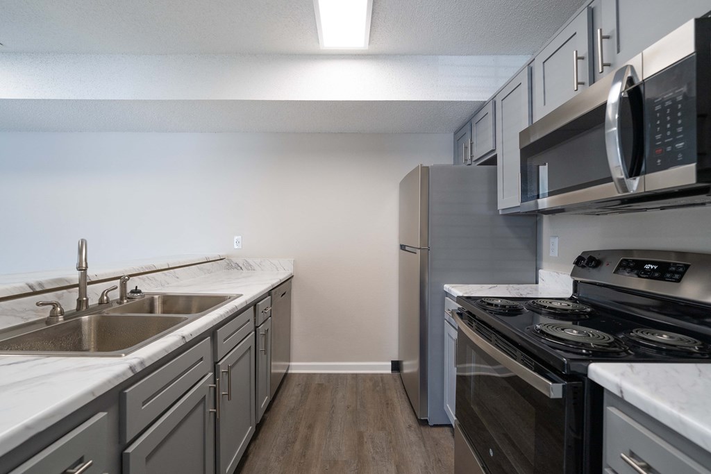 an empty kitchen with stainless steel appliances and white counter tops