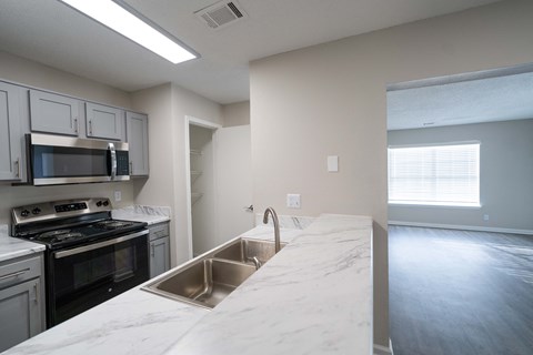 an empty kitchen with white marble counter tops and stainless steel appliances