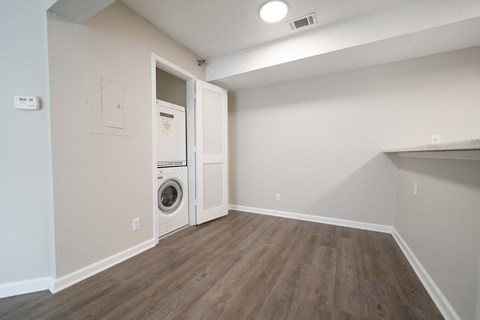 an empty room with a washer and dryer in it and a white wall