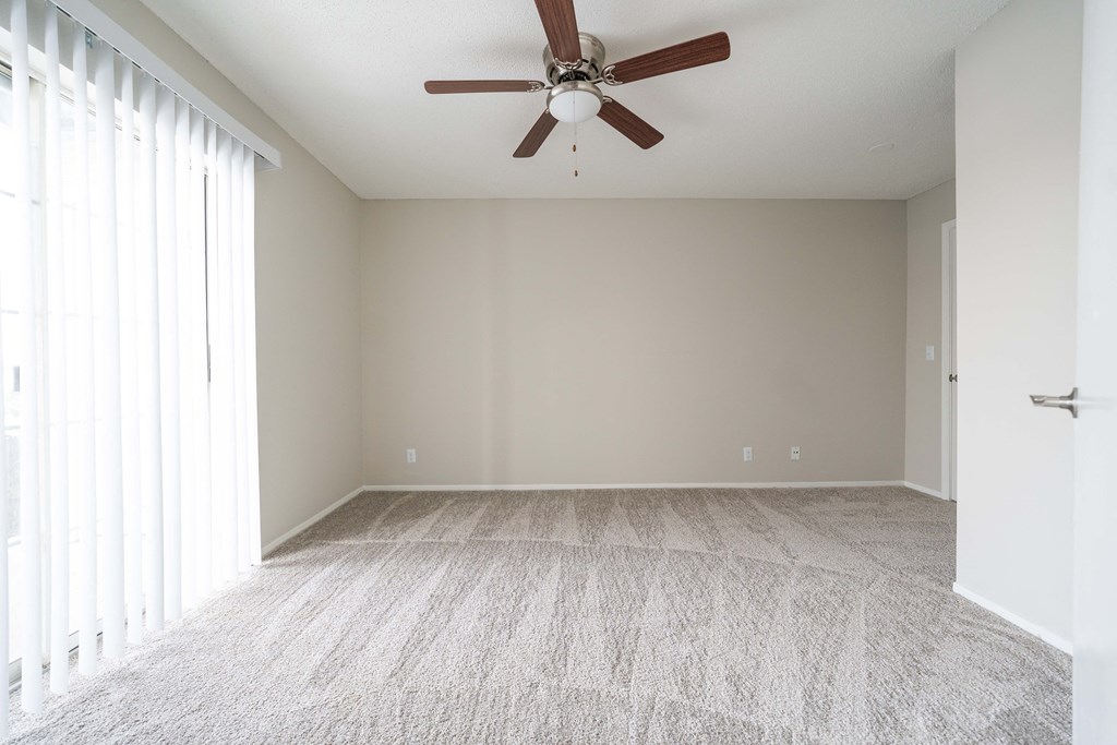 an empty living room with a ceiling fan