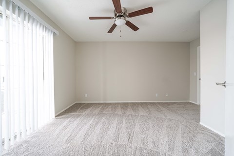 an empty living room with a ceiling fan