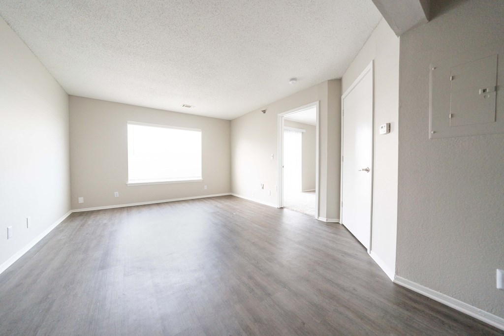 an empty living room with wood floors and white walls