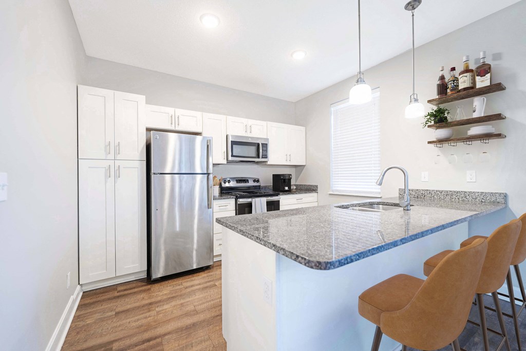 a kitchen with a marble counter top and a stainless steel refrigerator