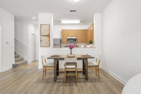 A dining room with a table set for two and a kitchen area in the background.