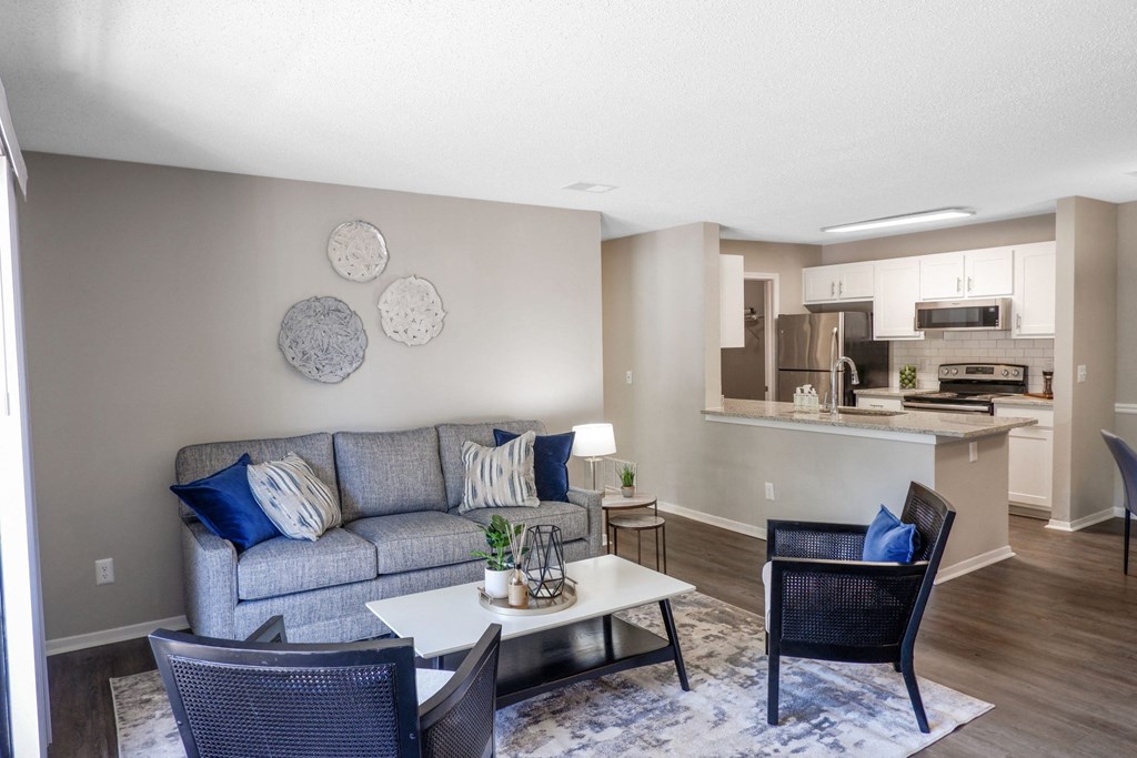 1 Park Central Apartments in Peachtree Corners photo of a living room with a couch coffee table and chairs and a kitchen in the background